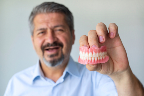 older man holding dentures